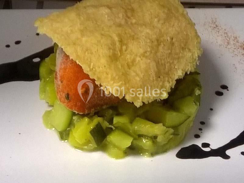 Plat composé de légumes verts en dés, d'une croquette orange et d'une tuile croustillante, avec une sauce noire décorative.