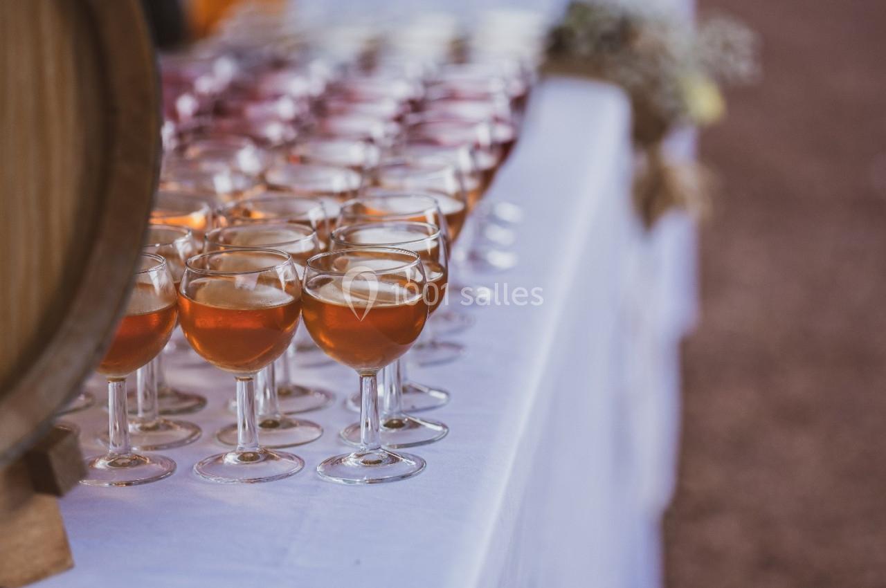 Verres de vin rosé alignés sur une table blanche lors d'un événement en extérieur.