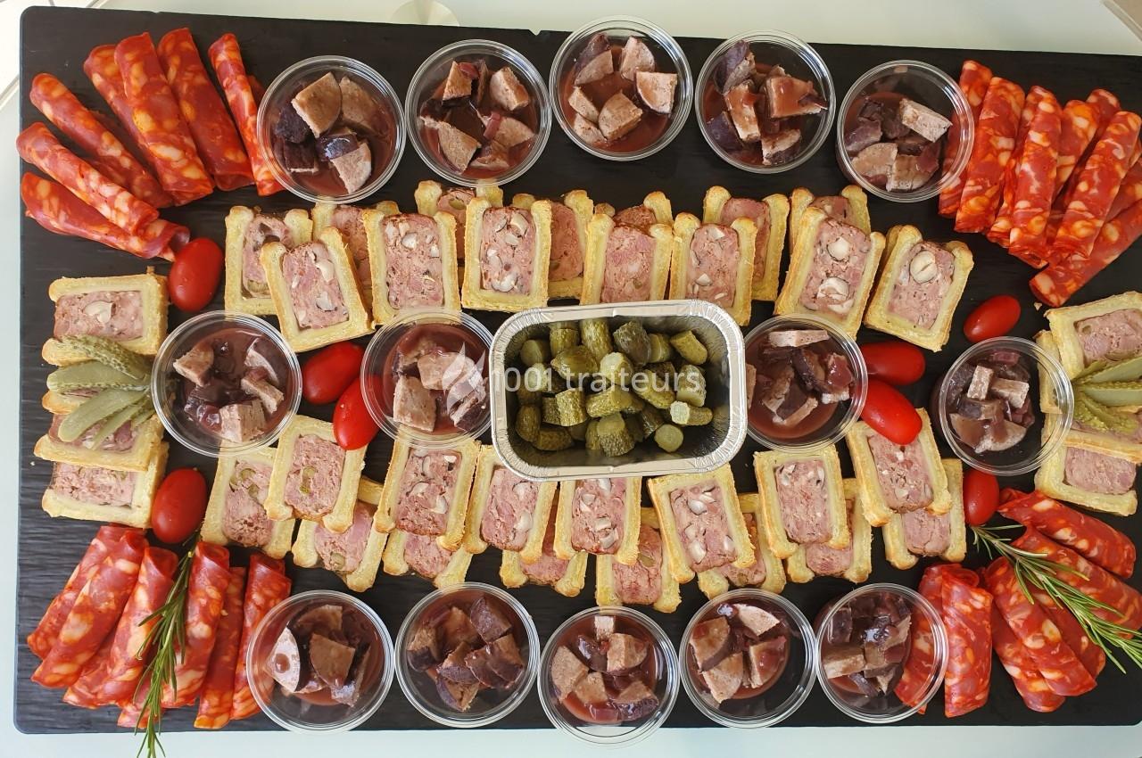 Plateau de charcuterie avec pâtés, saucissons, cornichons, tomates cerises et ramequins de terrines disposés symétriquement.