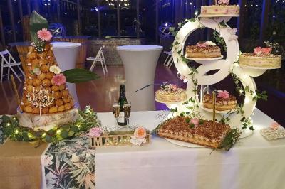 Tour de choux décorée avec des fleurs et des étincelles, entourée de desserts sur une table de réception.