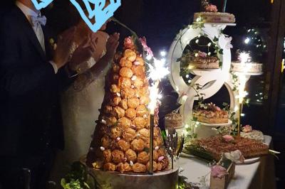 Tour de choux décorée avec des fleurs et des étincelles, entourée de desserts sur une table de réception.