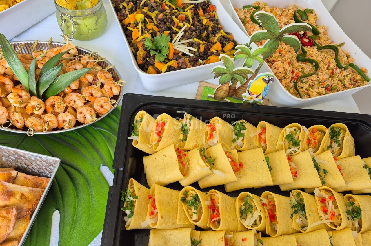 Plateau de wraps garnis entouré de plats variés, incluant riz, légumes, brochettes et salade colorée.