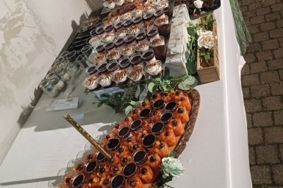 Buffet d'anniversaire en extérieur avec nappes blanches, plats variés, boissons et décor champêtre.