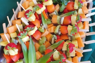 Buffet d'anniversaire en extérieur avec nappes blanches, plats variés, boissons et décor champêtre.