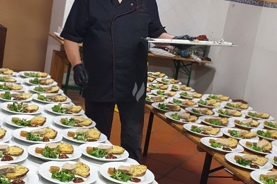 Buffet d'anniversaire en extérieur avec nappes blanches, plats variés, boissons et décor champêtre.