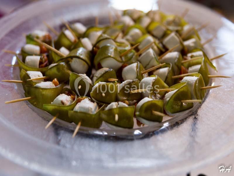 Brochettes apéritives composées de morceaux de fromage, fruits secs et lamelles de légumes verts sur un plateau.