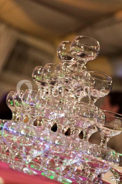 Une pyramide de coupes en verre empilées, éclairée par des lumières colorées dans un cadre festif.