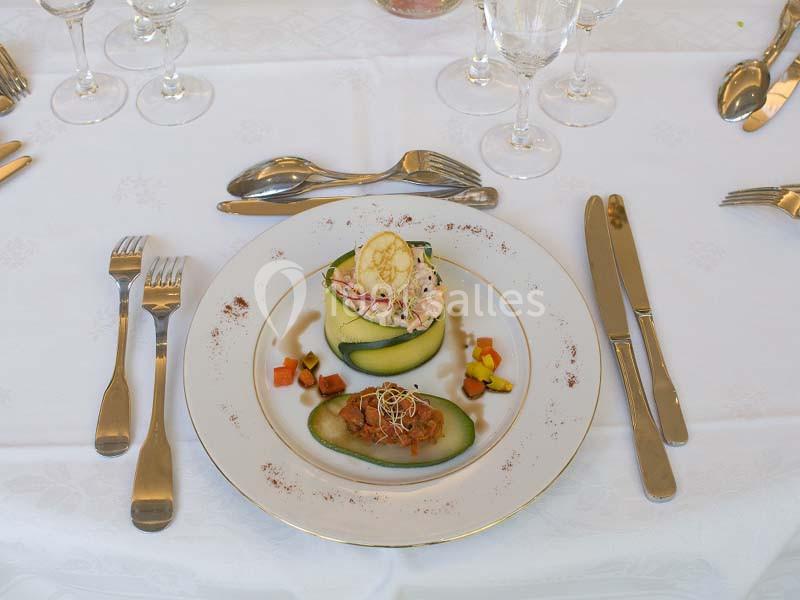 Assiette dressée avec une entrée raffinée à base de légumes et garniture, sur une table élégamment mise.