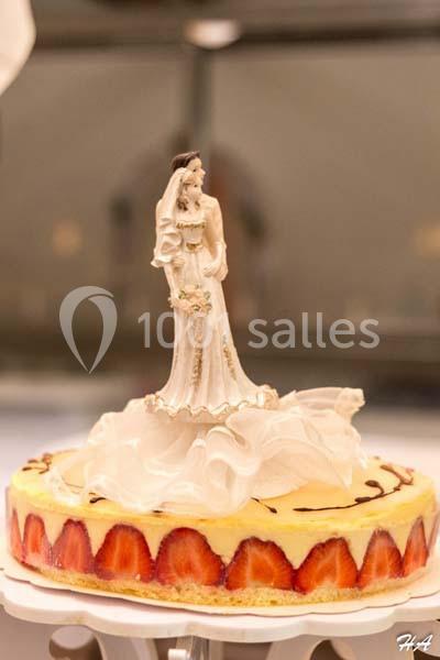 Gâteau de mariage décoré de fraises et surmonté d'une figurine représentant un couple de mariés.