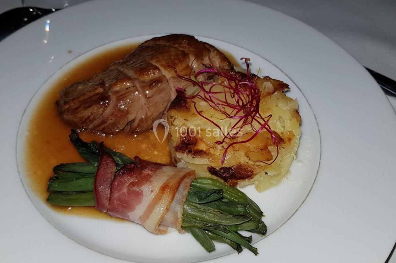 Assiette composée d'un filet de viande avec sauce, gratin de pommes de terre et haricots verts enroulés de lard.