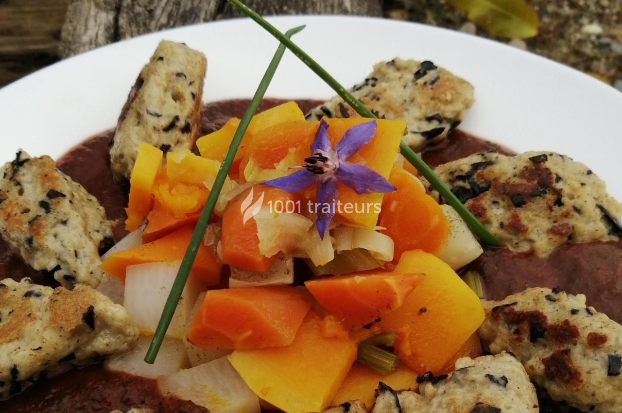 Assiette de légumes colorés avec quenelles grillées, garnie d'une fleur comestible et de brins de ciboulette.