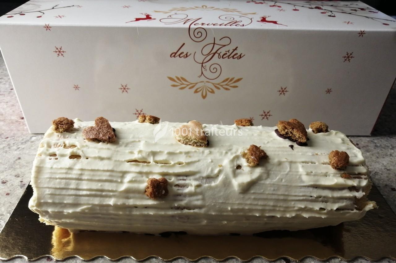 Bûche de Noël décorée de biscuits en forme d'étoiles, présentée devant une boîte festive.
