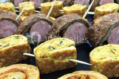 Plateau à étages avec des coquilles garnies de crevettes, légumes et herbes, présenté sur une table de buffet.