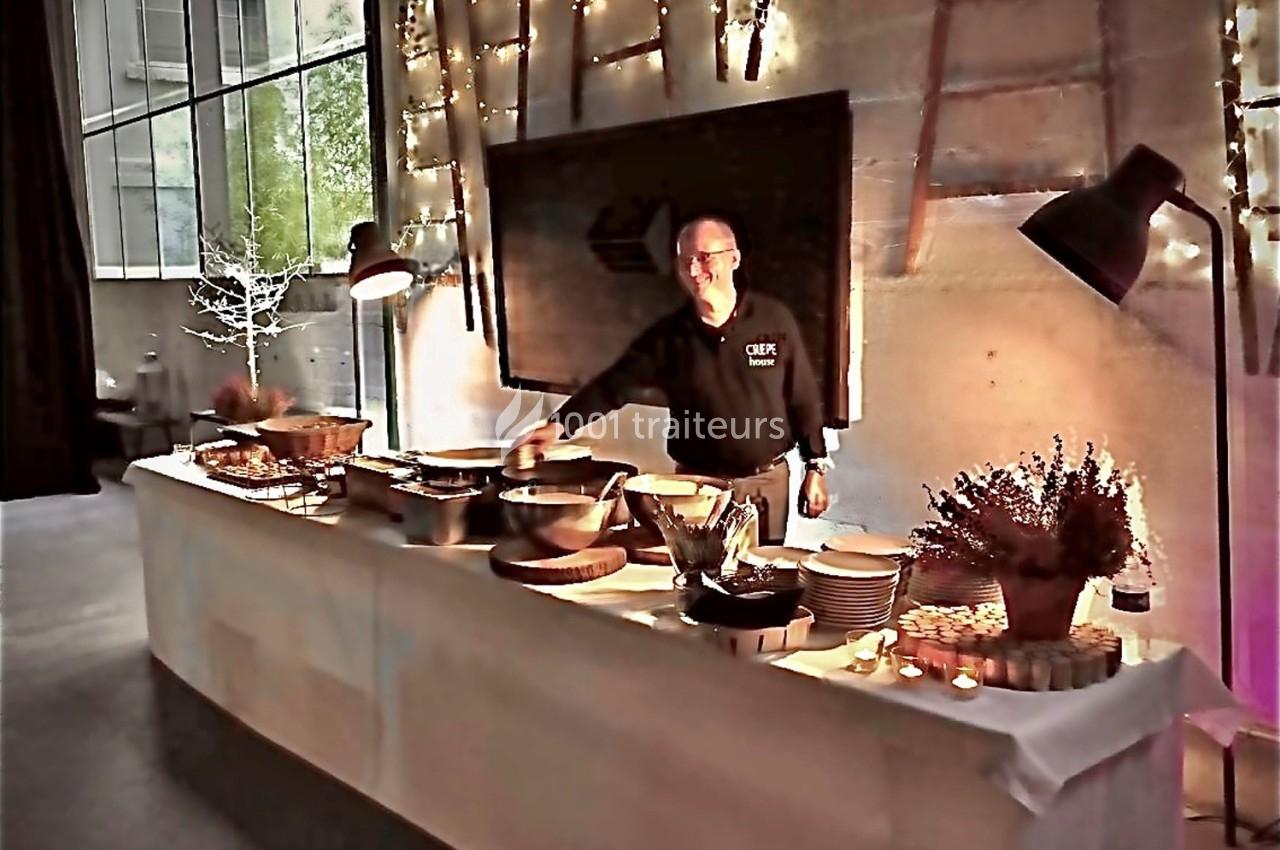 Un chef derrière un buffet décoré, proposant des plats dans une salle éclairée par des guirlandes lumineuses.