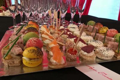 Plateau de mini-burgers colorés et assortiments de canapés sur une table dressée pour un buffet.