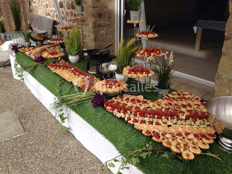 Buffet en extérieur avec une variété de plats et amuse-bouches disposés sur une table recouverte de gazon artificiel.