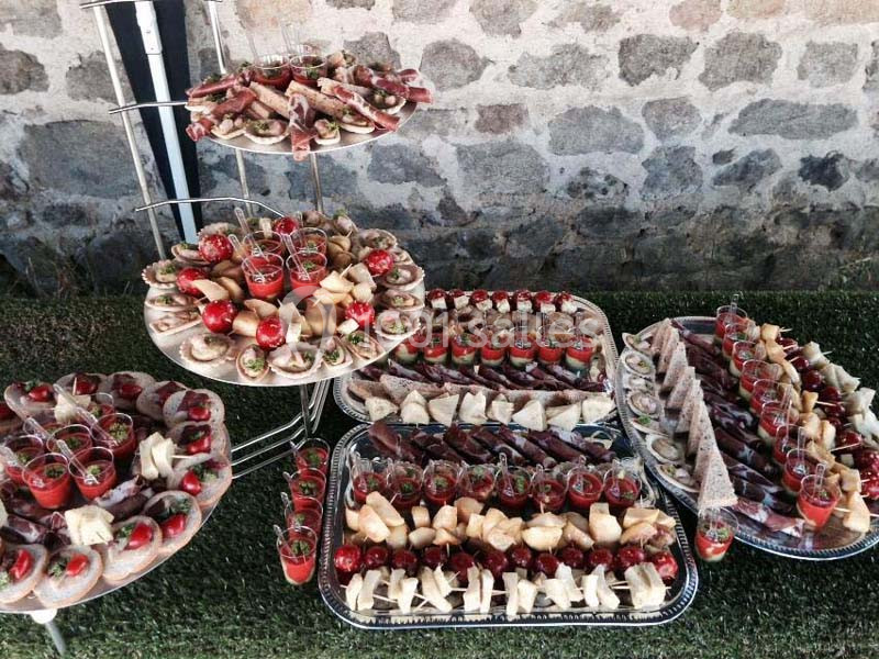 Plateaux garnis de canapés, verrines et amuse-bouches variés disposés sur une table en extérieur.