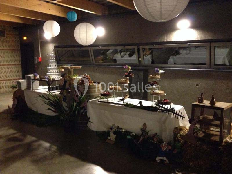 Table décorée avec des desserts et des éléments rustiques dans une salle avec éclairage tamisé et lanternes suspendues.