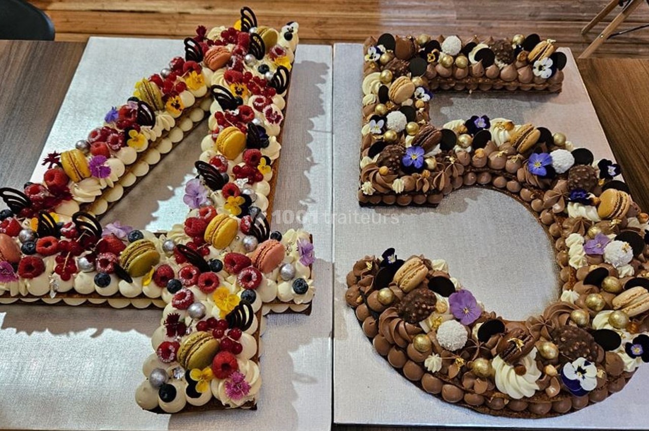 Gâteaux en forme de chiffres 4 et 5, décorés de fruits, macarons, fleurs comestibles et chocolats.