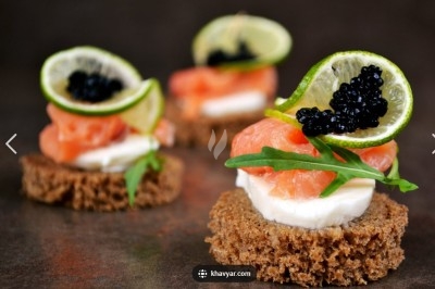 Plateau de mini-burgers, bouchées variées et garnitures sur une ardoise noire, présenté sur une nappe sombre.