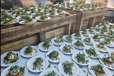 Plateau de mini-burgers, bouchées variées et garnitures sur une ardoise noire, présenté sur une nappe sombre.