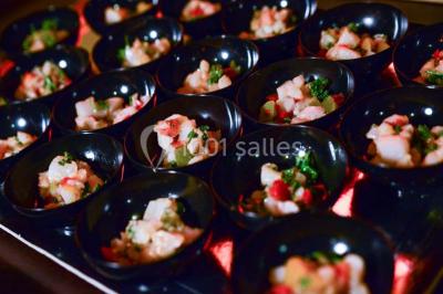 Plateau de mini-burgers, bouchées variées et garnitures sur une ardoise noire, présenté sur une nappe sombre.