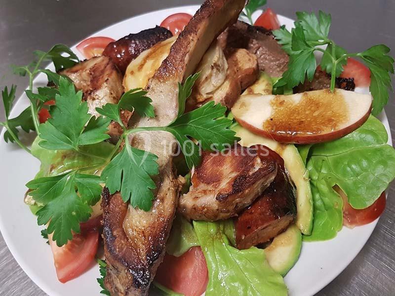 Assiette de salade garnie de côtes de porc grillées, pommes, avocat, tomates et feuilles de persil.