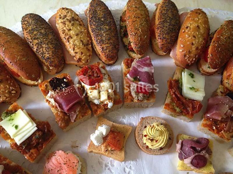 Plateau de mini sandwichs et amuse-bouches variés avec garnitures de charcuterie, fromage et légumes.