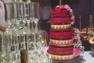 Miniature Traiteur Cuverville (Calvados) - Traiteur Calvados #23 Tour de coupes en verre illuminée et gâteau à étages décoré de fleurs roses sur une table de réception.