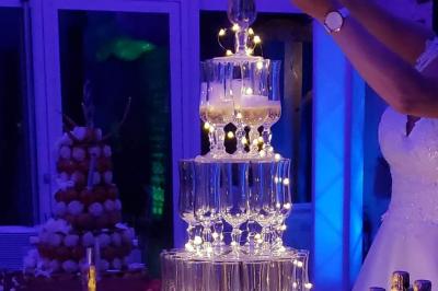 Miniature Traiteur Cuverville (Calvados) - Traiteur Calvados #3 Tour de coupes en verre illuminée et gâteau à étages décoré de fleurs roses sur une table de réception.