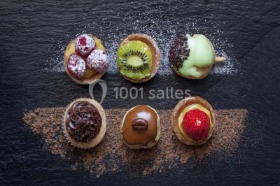 Buffet varié avec verrines, amuse-bouches, pains et pâtisseries disposés sur une table noire.