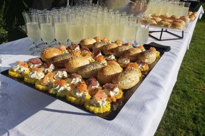 Buffet varié avec verrines, amuse-bouches, pains et pâtisseries disposés sur une table noire.