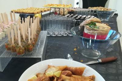 Buffet varié avec verrines, amuse-bouches, pains et pâtisseries disposés sur une table noire.