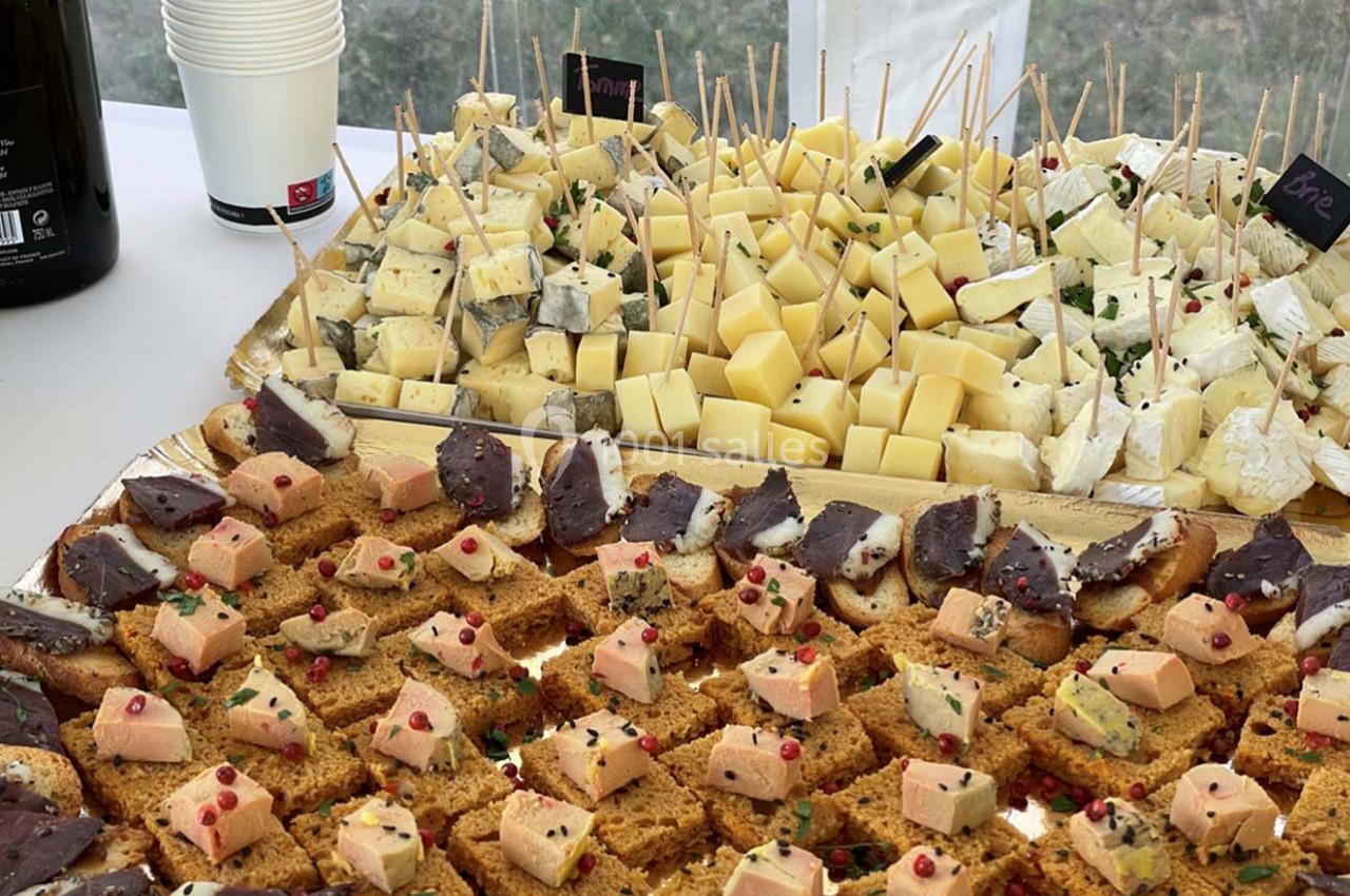 Plateau de fromages variés et toasts garnis de foie gras et condiments, présenté sur une table de réception.