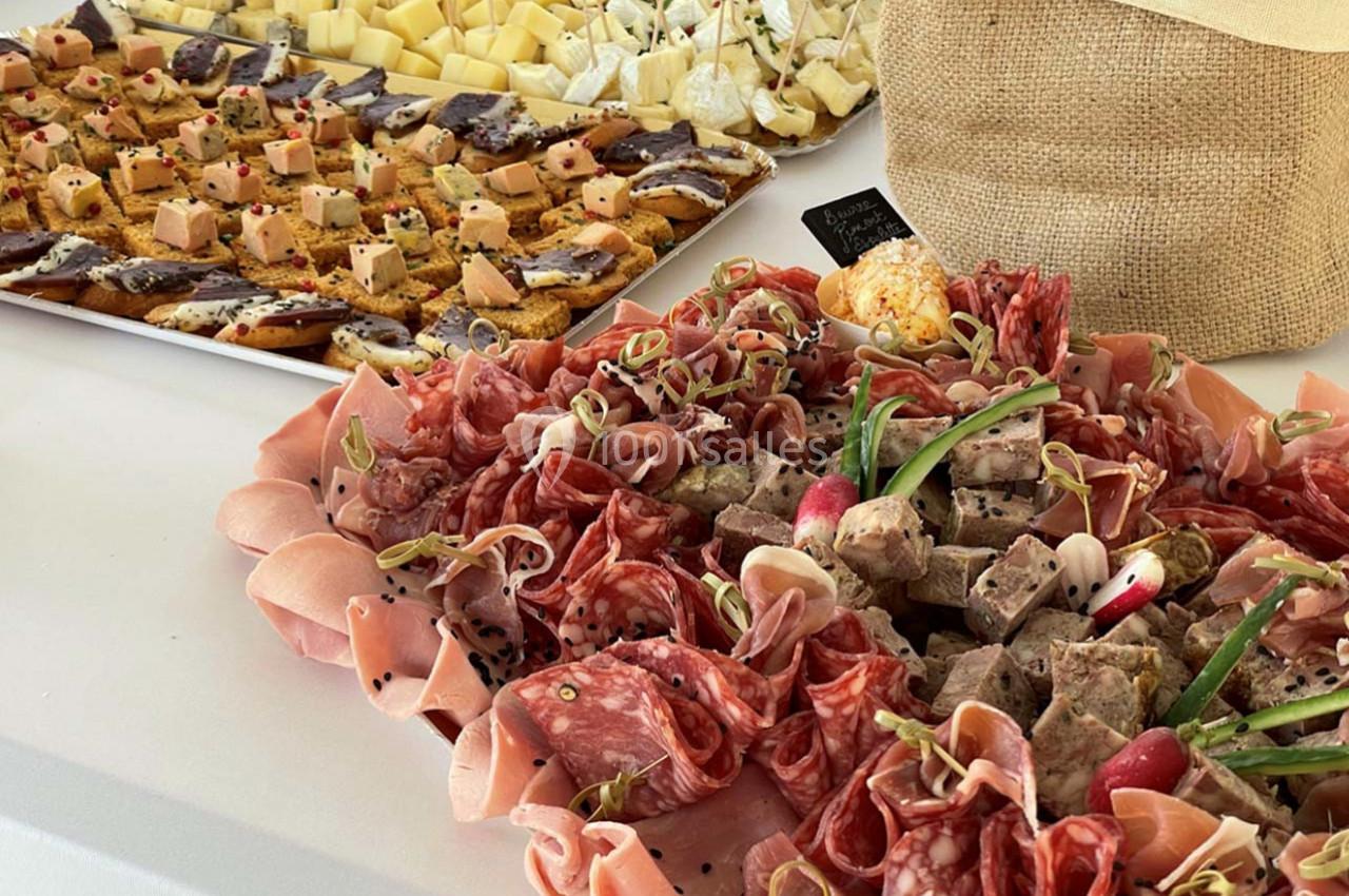 Plateau de charcuterie, fromages et toasts garnis, présenté sur une table blanche pour un buffet ou apéritif.