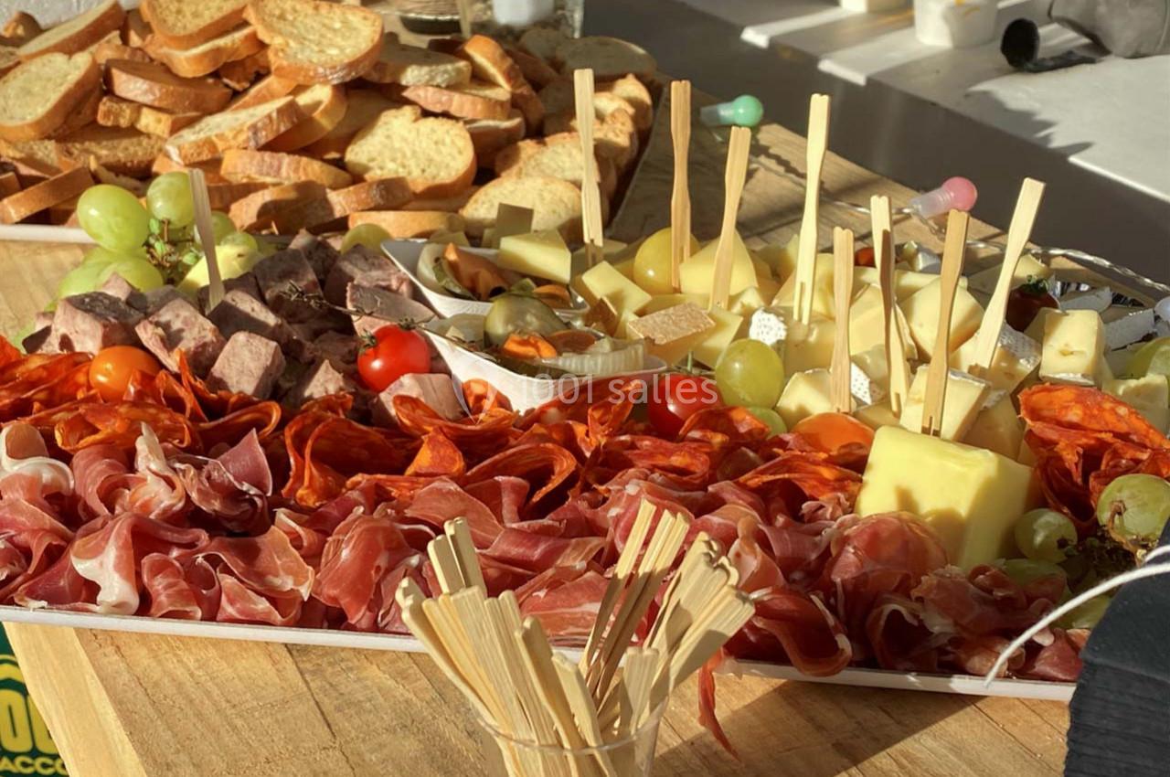 Plateau de charcuterie et fromages variés avec raisins, tomates cerises et pain grillé sur une table en bois.