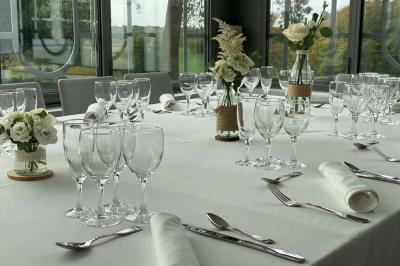 Table décorée pour un repas festif avec nappes blanches, verres, bougies, décorations végétales et petits cadeaux.