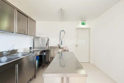 Miniature Traiteur Magny-le-Hongre (Seine-et-Marne) - Rubis Receptions #27 Cuisine professionnelle avec plans de travail en inox, évier, robinet flexible et porte de sortie au fond.