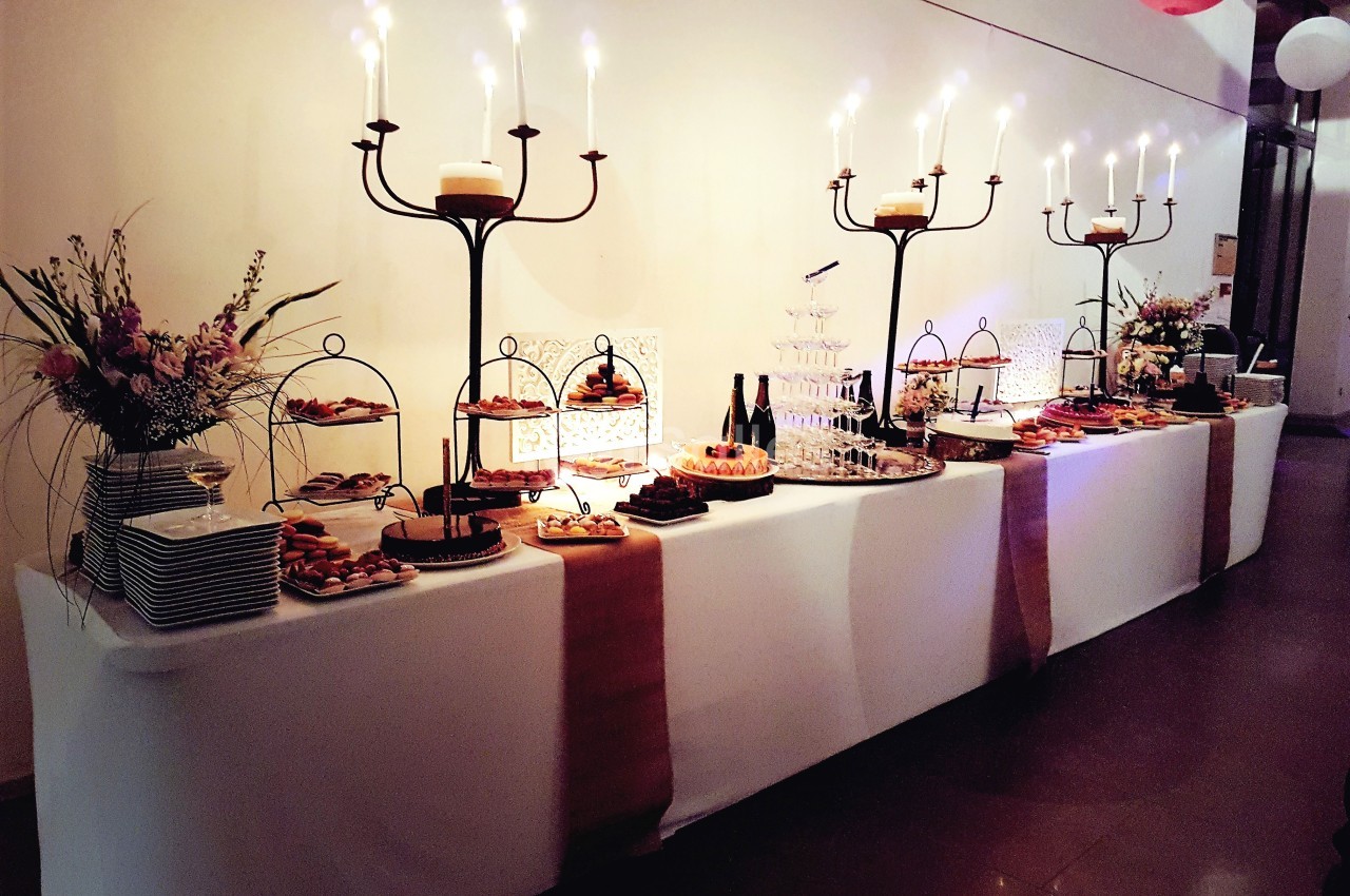 Table de buffet élégamment décorée avec chandeliers, fleurs et divers plats sucrés et salés.