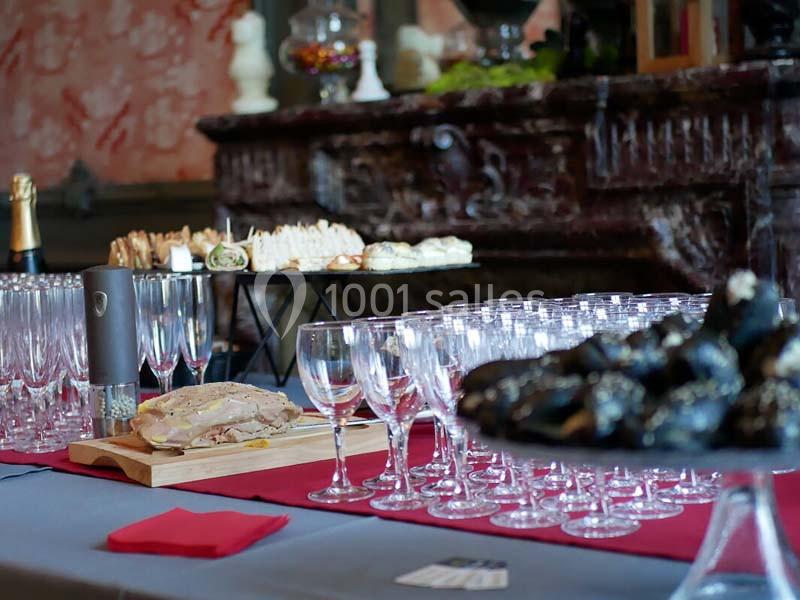 Table dressée avec des verres à vin, foie gras, amuse-bouches et truffes devant une cheminée décorative.