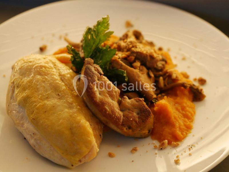 Assiette contenant un suprême de volaille, purée de carottes et garniture de champignons avec herbes fraîches.
