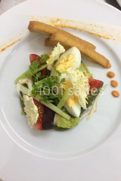 Assiette composée de légumes frais, œuf dur, frites et sauce, présentée sur une assiette blanche.