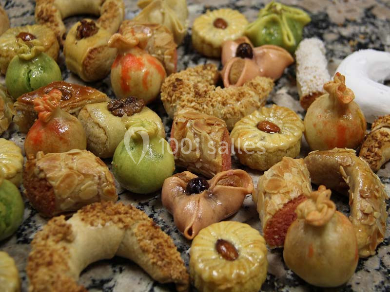 Assortiment de pâtisseries traditionnelles aux formes variées, décorées d'amandes, fruits secs et glaçages colorés.