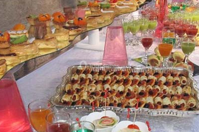 Miniature Traiteur Saint-Cyr-en-Val (Loiret) - Royal Events Traiteur et Tradition #3 Un homme en tenue traditionnelle sert du thé près d'une table garnie de pâtisseries et de verres dans une salle lumineuse.