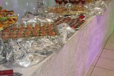 Miniature Traiteur Saint-Cyr-en-Val (Loiret) - Royal Events Traiteur et Tradition #7 Un homme en tenue traditionnelle sert du thé près d'une table garnie de pâtisseries et de verres dans une salle lumineuse.