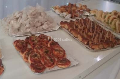 Miniature Traiteur Saint-Cyr-en-Val (Loiret) - Royal Events Traiteur et Tradition #8 Un homme en tenue traditionnelle sert du thé près d'une table garnie de pâtisseries et de verres dans une salle lumineuse.