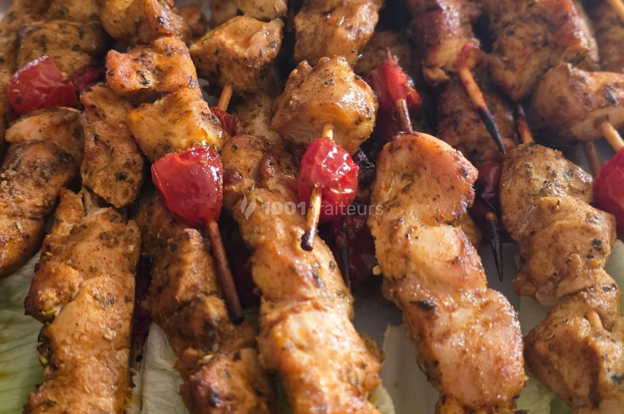 Brochettes de poulet grillé assaisonnées, garnies de morceaux de poivrons rouges, servies sur un lit de salade.