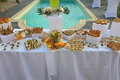 Miniature Traiteur Saint-Cyr-en-Val (Loiret) - Royal Events Traiteur et Tradition #18 Un homme en tenue traditionnelle sert du thé près d'une table garnie de pâtisseries et de verres dans une salle lumineuse.