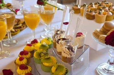 Miniature Traiteur Saint-Cyr-en-Val (Loiret) - Royal Events Traiteur et Tradition #24 Un homme en tenue traditionnelle sert du thé près d'une table garnie de pâtisseries et de verres dans une salle lumineuse.