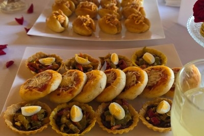 Miniature Traiteur Saint-Cyr-en-Val (Loiret) - Royal Events Traiteur et Tradition #25 Un homme en tenue traditionnelle sert du thé près d'une table garnie de pâtisseries et de verres dans une salle lumineuse.